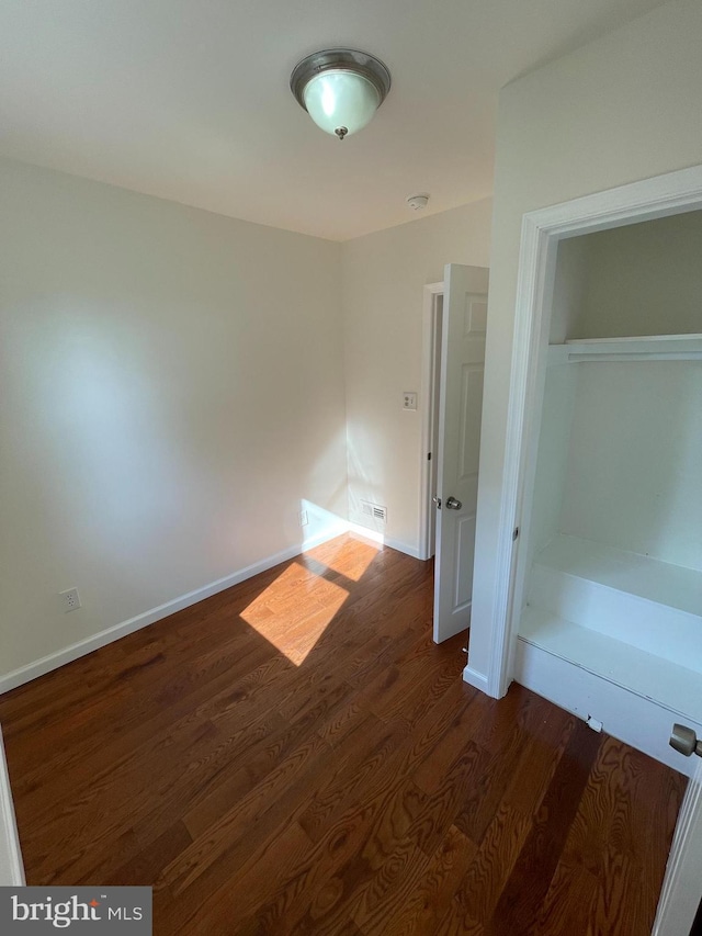 unfurnished bedroom with dark wood-type flooring and a closet