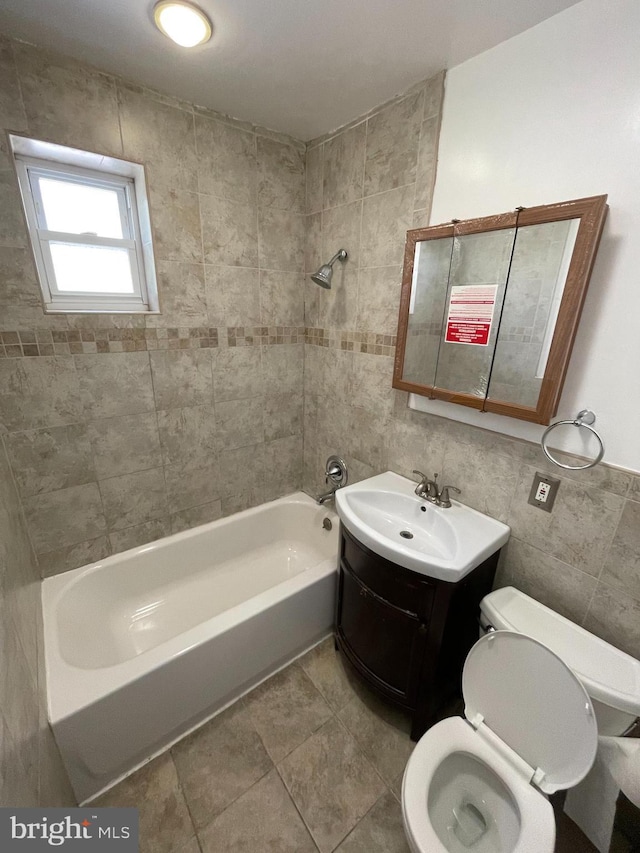 full bathroom with tile patterned flooring, toilet, vanity, tile walls, and tiled shower / bath