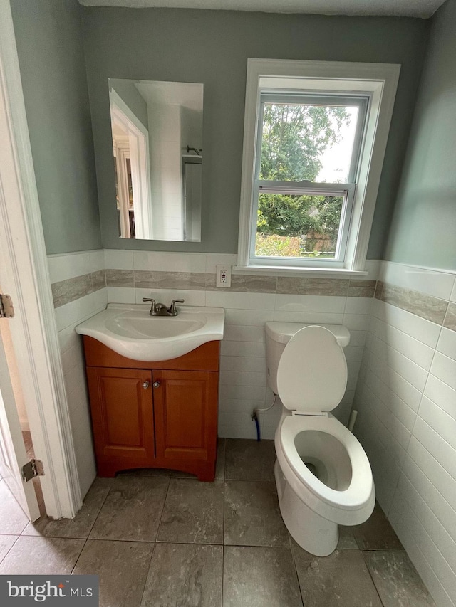 bathroom featuring tile patterned flooring, vanity, tile walls, and toilet