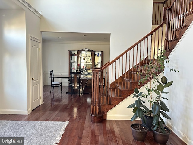 stairway featuring hardwood / wood-style floors, an inviting chandelier, and ornamental molding