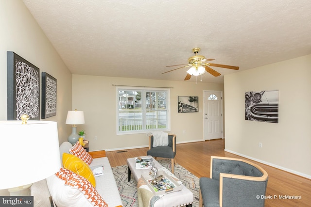 living room featuring a textured ceiling, hardwood / wood-style flooring, and ceiling fan