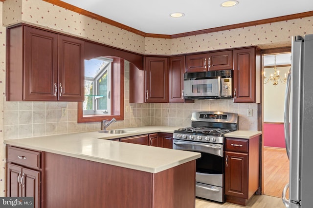 kitchen featuring sink, crown molding, light wood-type flooring, appliances with stainless steel finishes, and kitchen peninsula