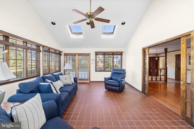 tiled living room with a skylight, high vaulted ceiling, and ceiling fan