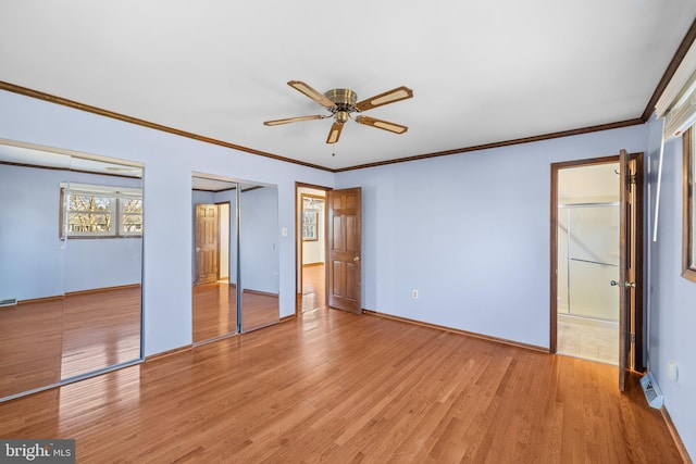 unfurnished bedroom with multiple closets, ornamental molding, ceiling fan, and light hardwood / wood-style flooring