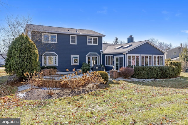 view of front of property with a sunroom, a patio, and a front yard