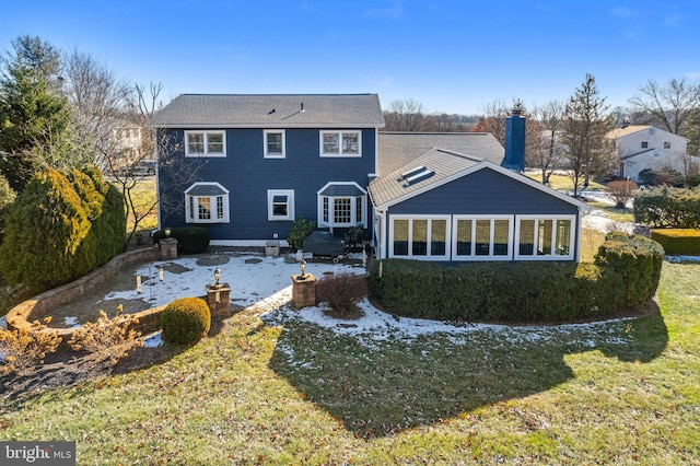 rear view of house with a lawn and a sunroom