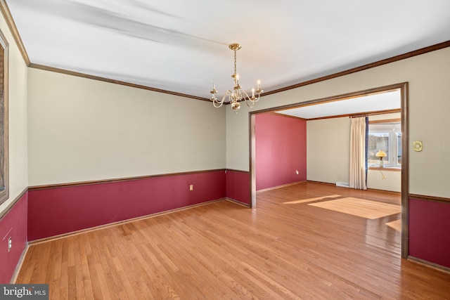 unfurnished room with a notable chandelier, crown molding, and hardwood / wood-style flooring