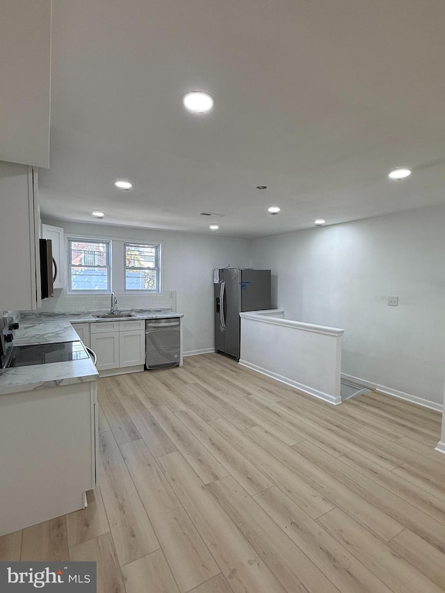 kitchen featuring white cabinetry, sink, light hardwood / wood-style flooring, and appliances with stainless steel finishes