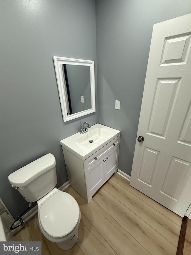 bathroom with wood-type flooring, vanity, and toilet