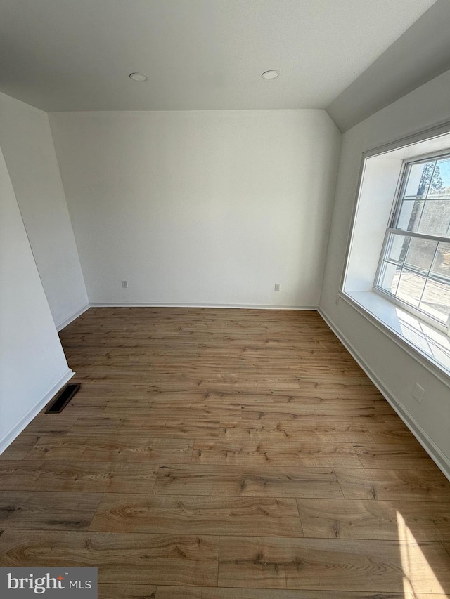 empty room with lofted ceiling and light hardwood / wood-style flooring