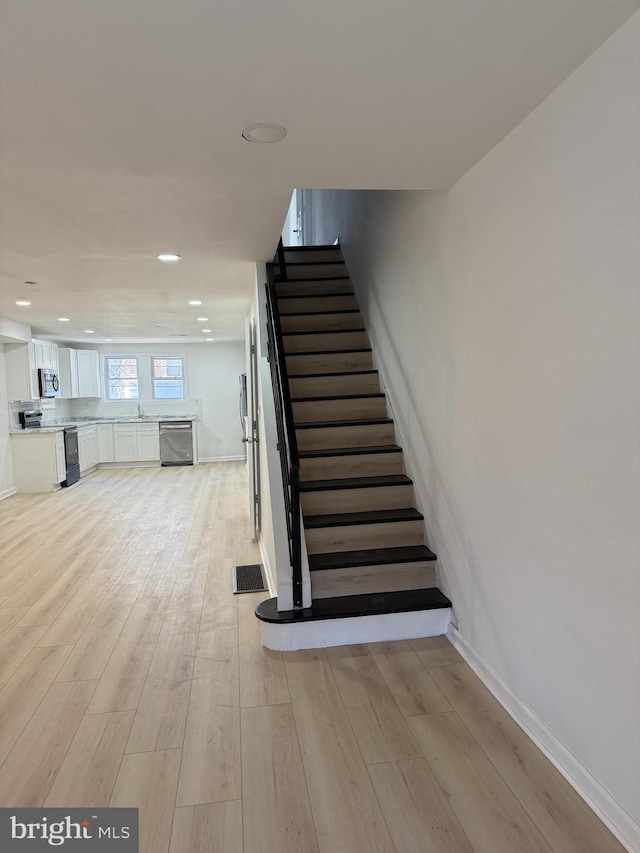 staircase featuring wood-type flooring and sink