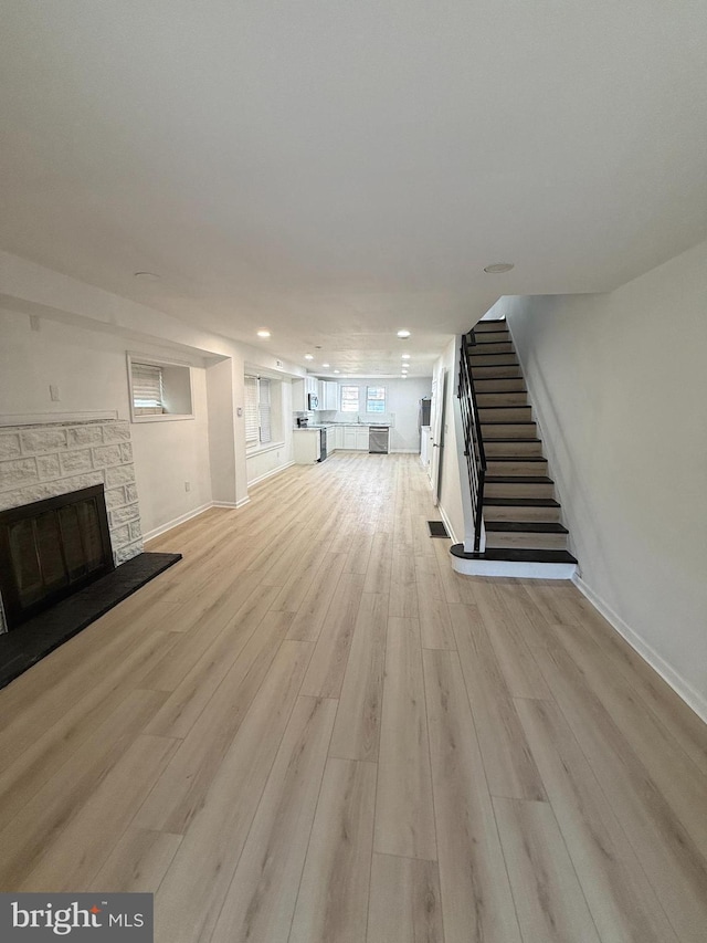 unfurnished living room featuring light hardwood / wood-style flooring and a stone fireplace