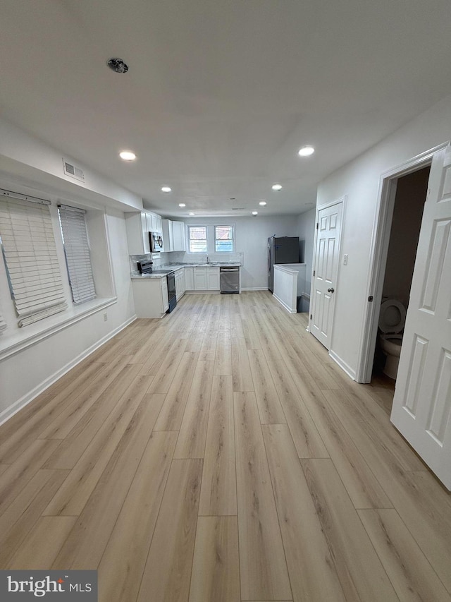 unfurnished living room featuring light wood-type flooring and sink