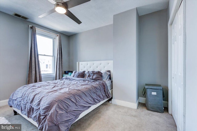 bedroom featuring light colored carpet, ceiling fan, and a closet