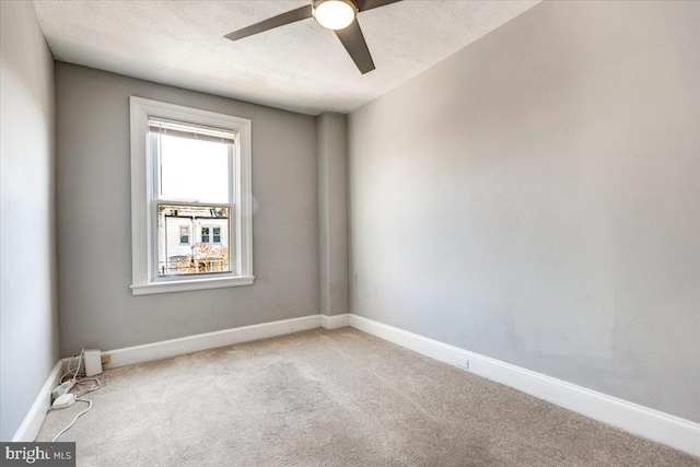 spare room with a textured ceiling, light colored carpet, and ceiling fan