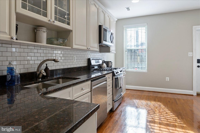 kitchen featuring sink, white cabinetry, dark stone countertops, dark hardwood / wood-style flooring, and stainless steel appliances