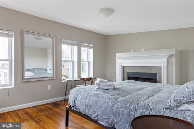 bedroom with a fireplace, hardwood / wood-style floors, and multiple windows