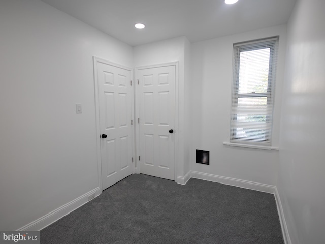 unfurnished room with dark colored carpet