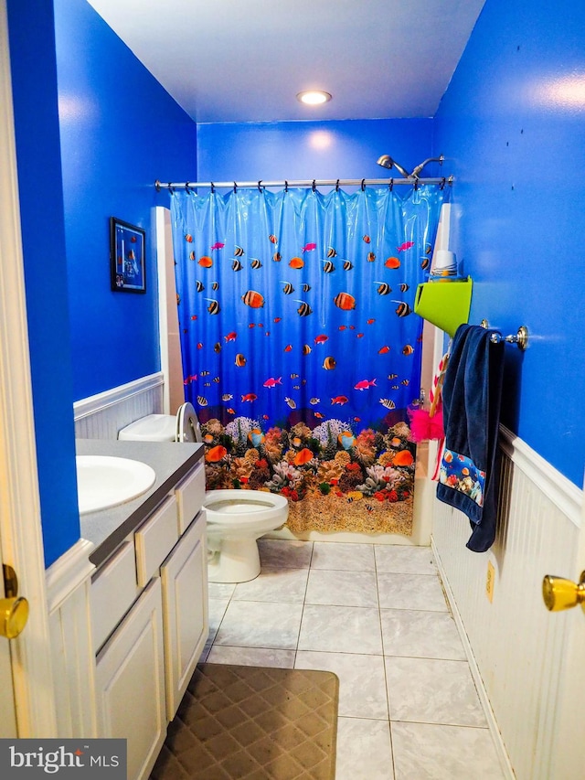 full bath featuring toilet, a wainscoted wall, tile patterned floors, and vanity