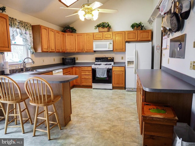 kitchen featuring brown cabinetry, dark countertops, white appliances, and a sink