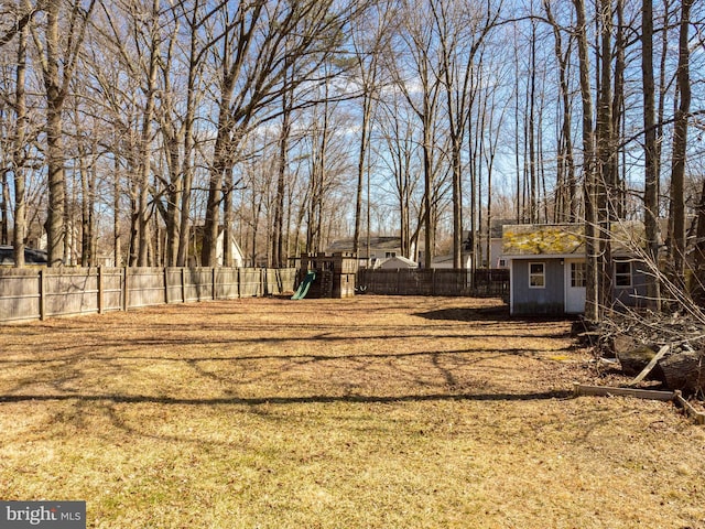 view of yard featuring a fenced backyard, a storage unit, a playground, and an outdoor structure