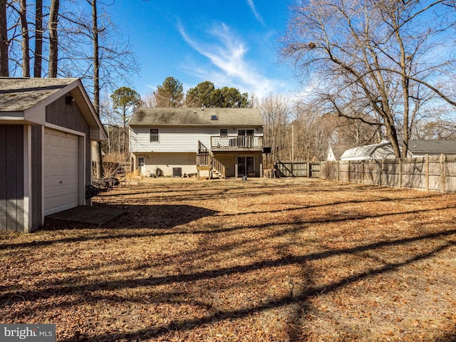 back of property featuring a garage, an outdoor structure, fence, stairway, and a wooden deck