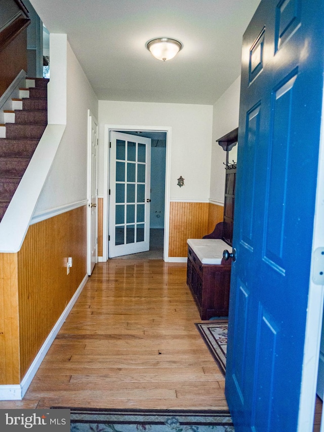 interior space with a wainscoted wall, wood walls, and wood finished floors