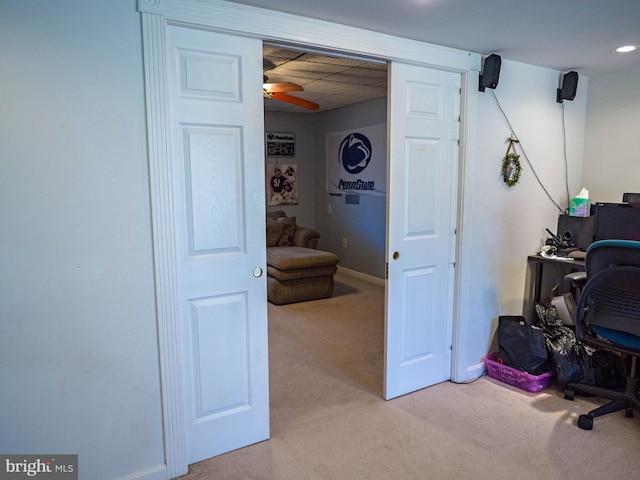 office area with a paneled ceiling, baseboards, a ceiling fan, and light colored carpet