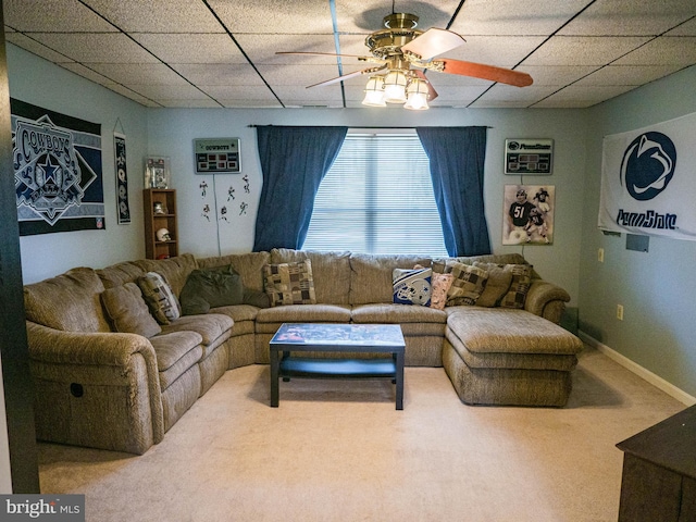 living room featuring ceiling fan, a drop ceiling, carpet flooring, and baseboards