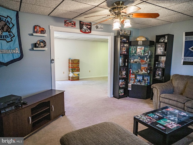 living area with carpet floors, a drop ceiling, ceiling fan, and baseboards