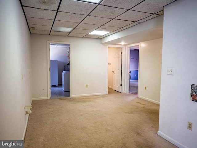 finished basement with washer / dryer, a paneled ceiling, light carpet, and baseboards