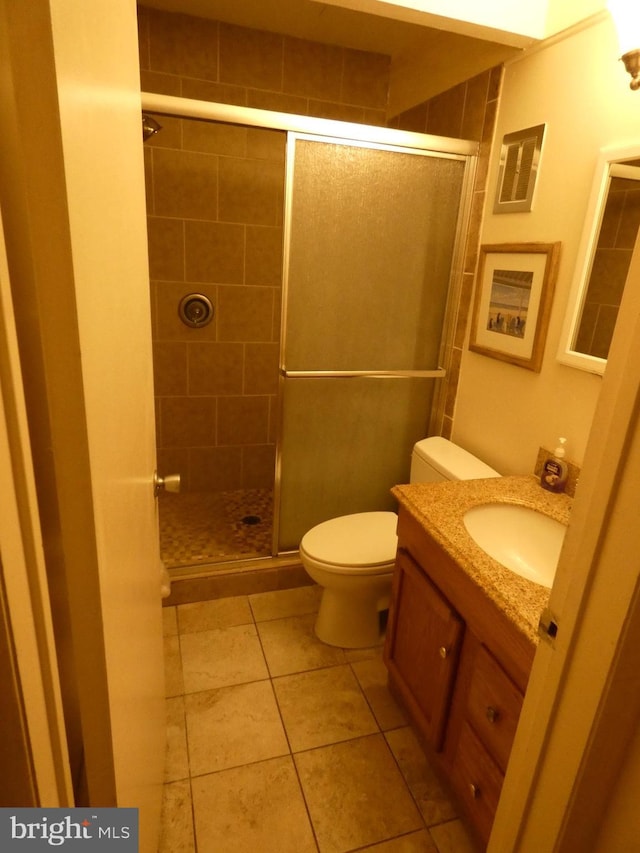 bathroom featuring vanity, toilet, walk in shower, and tile patterned flooring