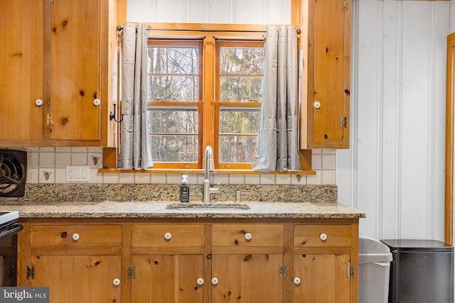 kitchen featuring backsplash, sink, and light stone counters