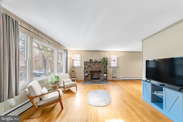 living room featuring a baseboard heating unit, a fireplace, and hardwood / wood-style floors