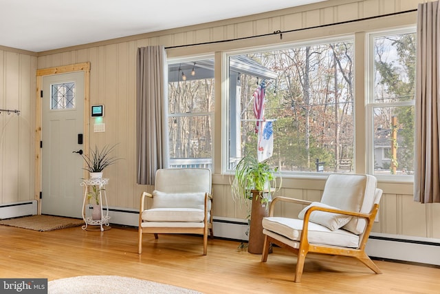 sitting room featuring a baseboard heating unit, light hardwood / wood-style flooring, and plenty of natural light