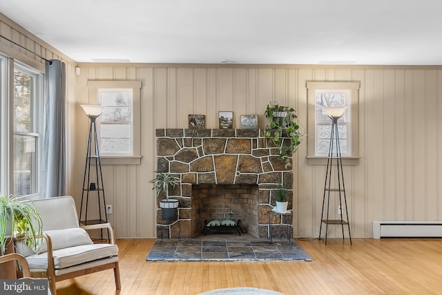 interior space with hardwood / wood-style flooring, a baseboard radiator, and a stone fireplace