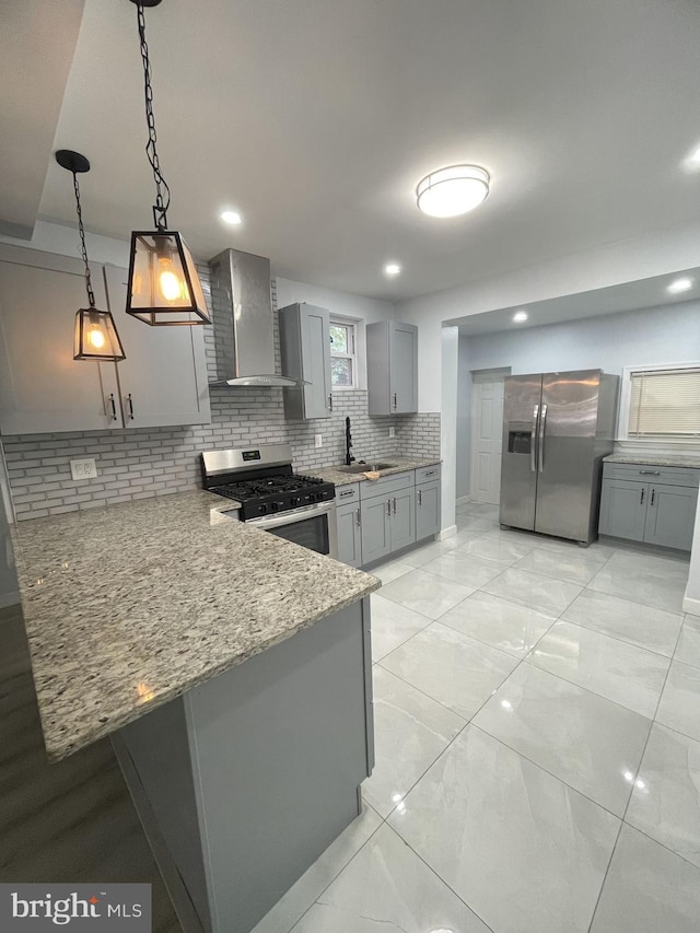 kitchen with kitchen peninsula, wall chimney range hood, hanging light fixtures, and appliances with stainless steel finishes