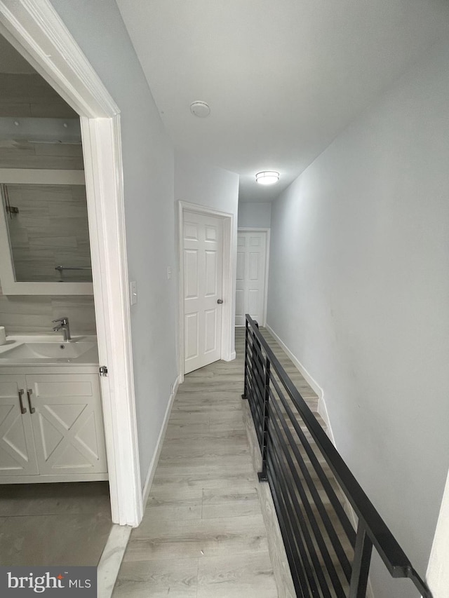 hall with light hardwood / wood-style floors and sink