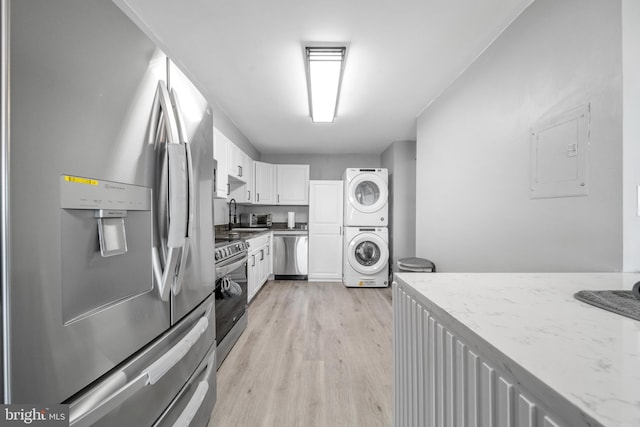 kitchen with light wood-style flooring, stainless steel appliances, stacked washer / dryer, white cabinetry, and electric panel