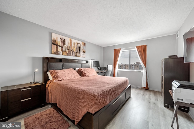 bedroom with light wood-style flooring and a textured ceiling