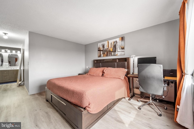 bedroom with a textured ceiling, light wood-style flooring, and baseboards