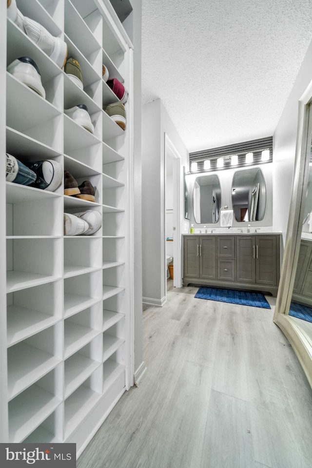 bathroom with vanity, baseboards, a textured ceiling, and wood finished floors