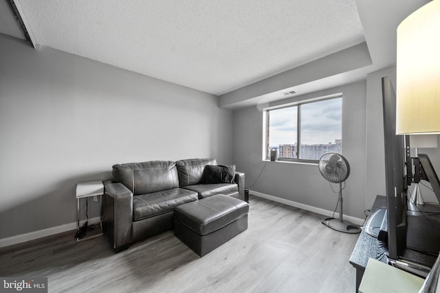 living room with a city view, a textured ceiling, baseboards, and wood finished floors