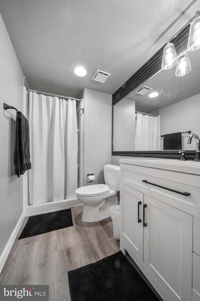 full bathroom featuring visible vents, vanity, a shower stall, and wood finished floors