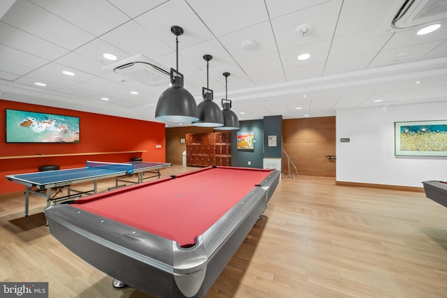 game room featuring an accent wall, light wood-type flooring, visible vents, and wooden walls