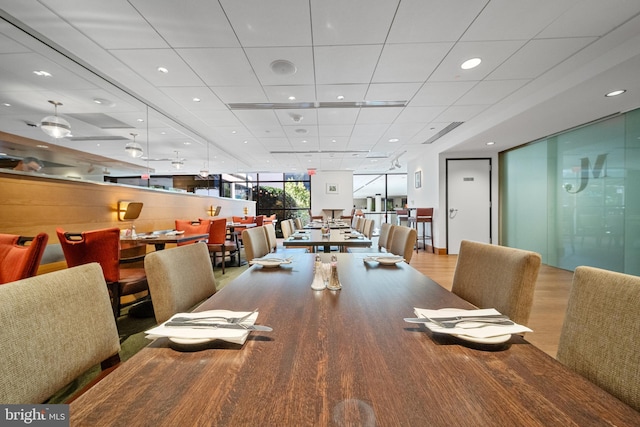 dining space featuring recessed lighting, a paneled ceiling, and wood finished floors