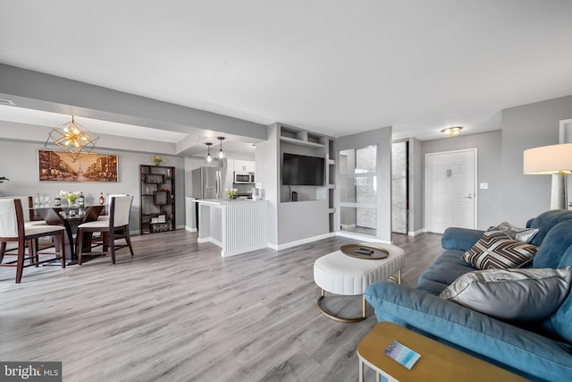 living area with a notable chandelier, baseboards, and wood finished floors