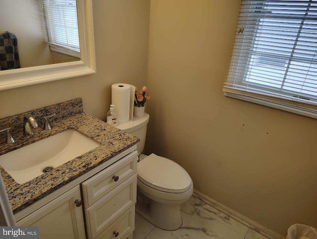 bathroom with vanity, toilet, and baseboards