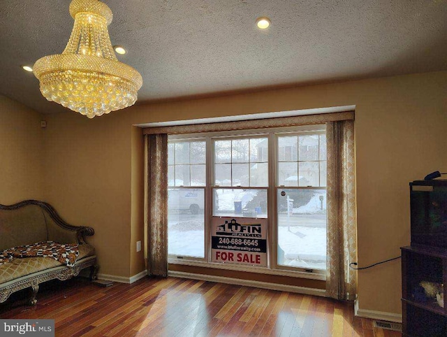 bedroom with a textured ceiling, hardwood / wood-style floors, and multiple windows