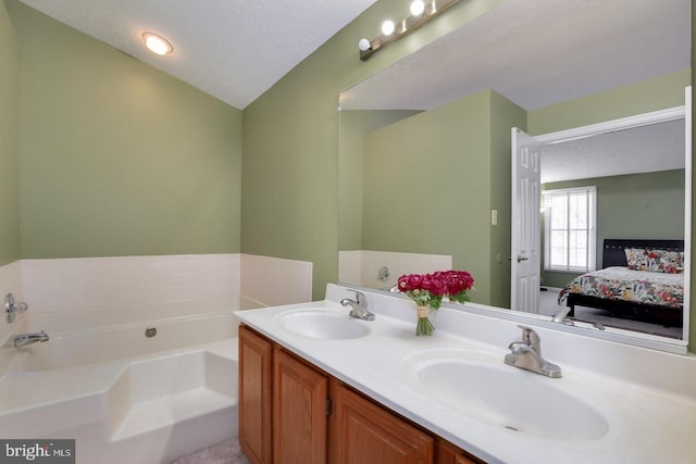 ensuite bathroom featuring a textured ceiling, ensuite bath, a sink, and a bath